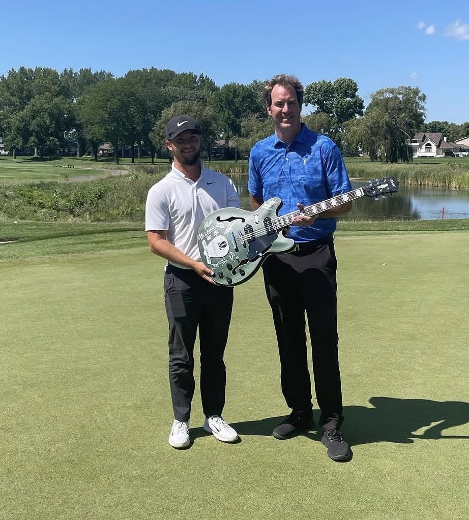 Zander receiving a signed guitar trophy on the green