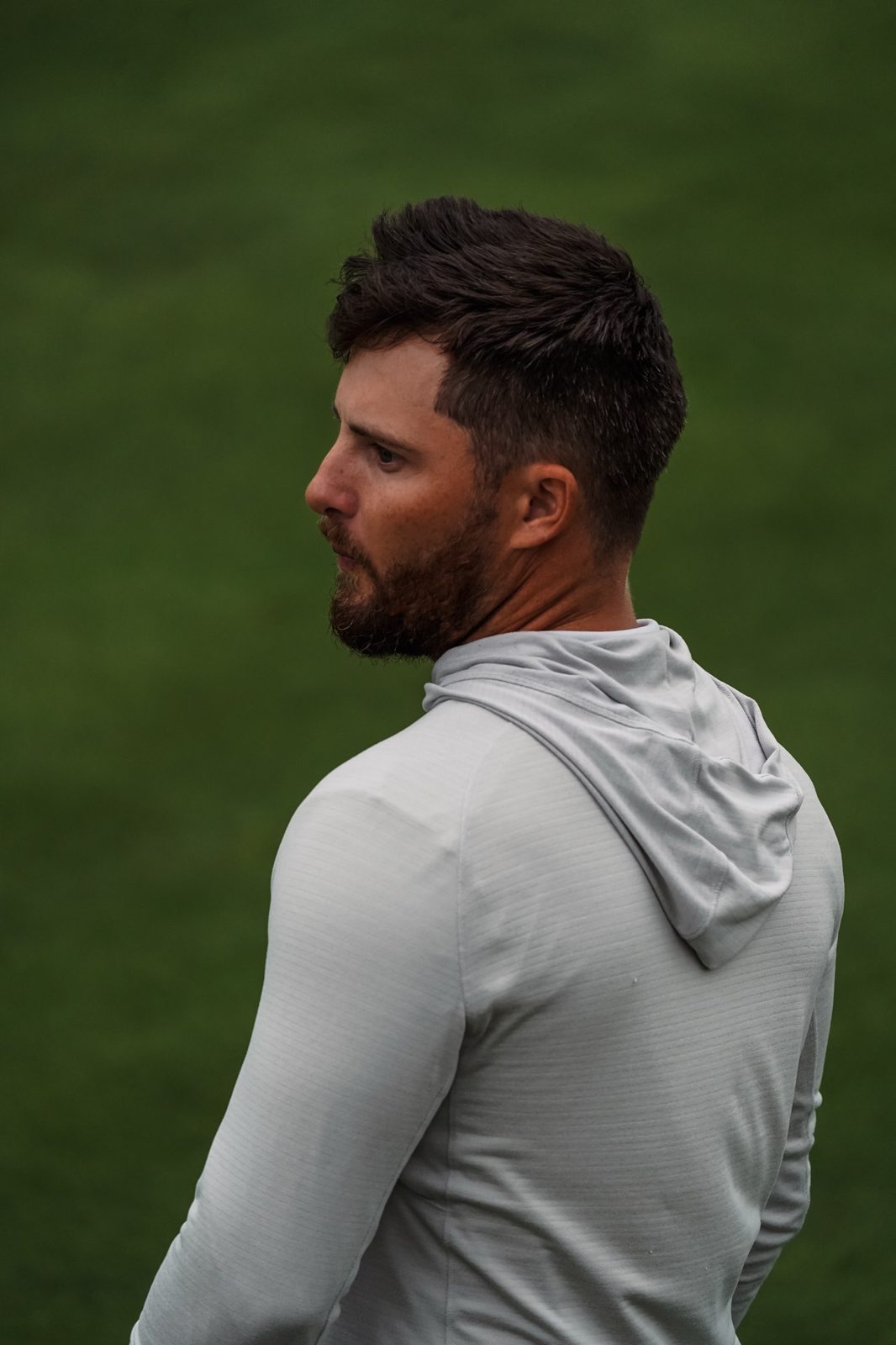 Zander Winston in profile on the course, wearing a gray hoodie