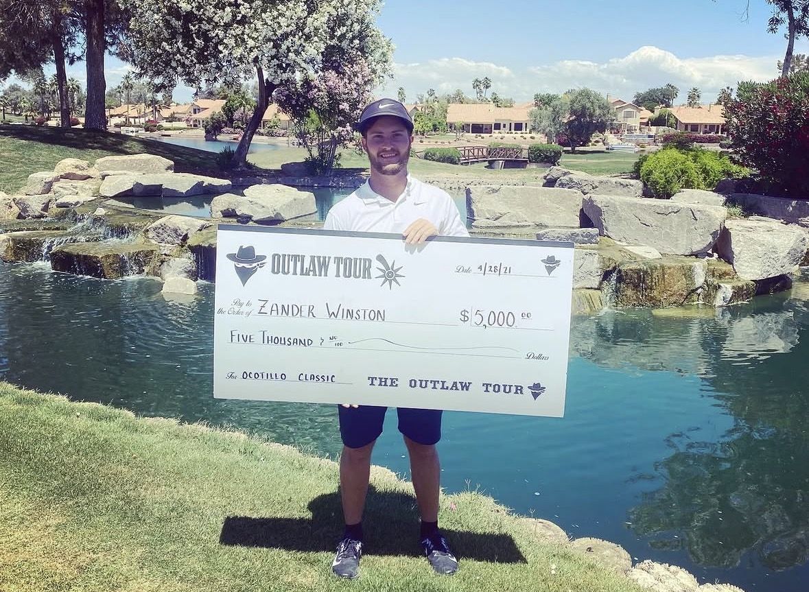 Zander holding the $5,000 Outlaw Tour Ocotillo Classic check beside a pond
