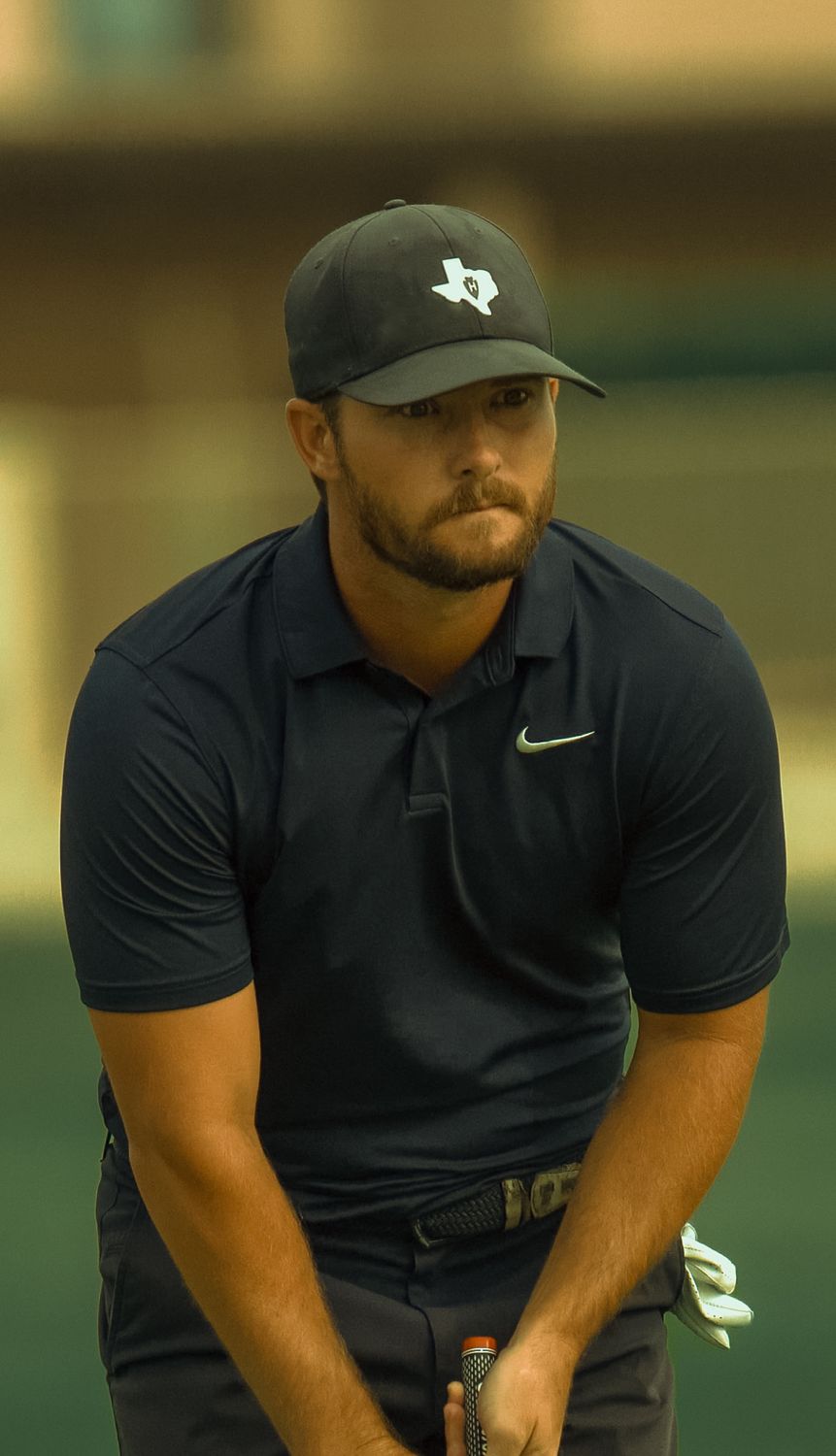 Zander in a Texas cap, focused over a putt