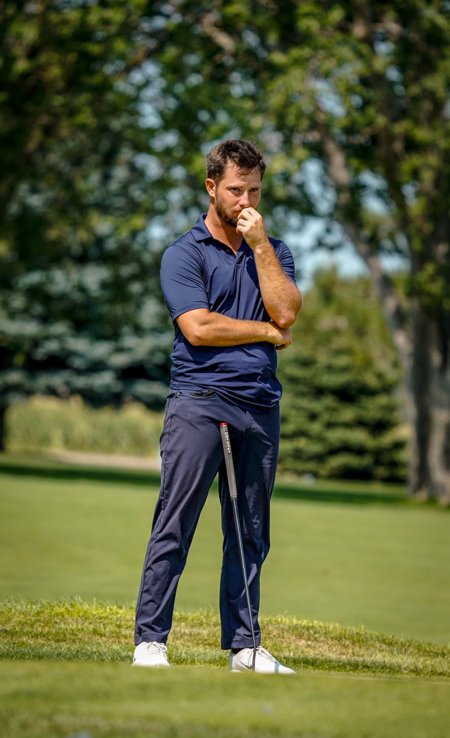Zander standing on the green, hand on chin, reading a putt